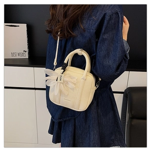 Detail of creamy white Boston bag with litchi texture, fashion logo and floral charm