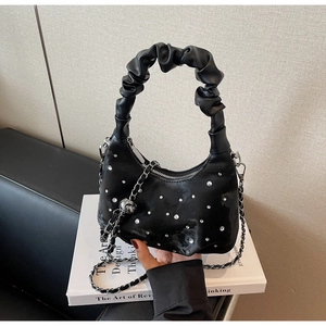 Close-up of black pleated dumpling bag with scattered rhinestones and silver chain strap
