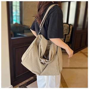 Detail of canvas tote bag with check pattern, leather buckle, and detachable shoulder strap