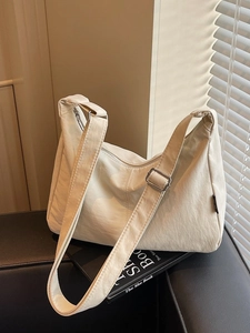 Minimalist beige canvas dumpling bag with adjustable wide strap in natural soft sunlight