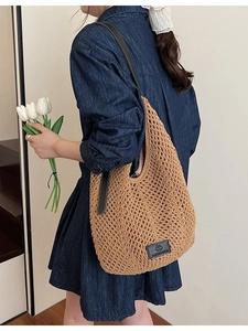 Brown woven crochet tote bag with hollow mesh design and leather shoulder strap on model