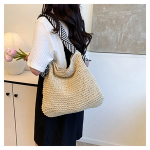 Vista dettagliata della borsa tote in paglia beige con tracolla a righe bianche e nere