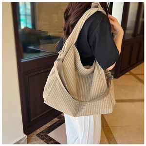 Detail view of khaki checkered canvas tote bag showing large capacity on model