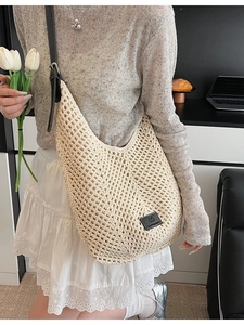 Beige crochet shoulder bag with hollow knit design and black leather straps and logo