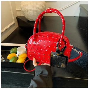 Detail of red patent leather bowling bag with heart pattern and luggage tag on stairs