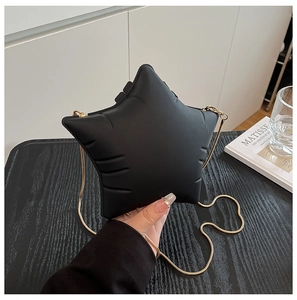Detail of a matte black star-shaped crossbody bag with a gold chain strap and embossed design