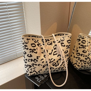 Detail of leopard print tote bag with cream handles reflected on a mirror surface