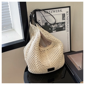 Close-up of cream woven tote bag with hollow knit texture and black leather strap
