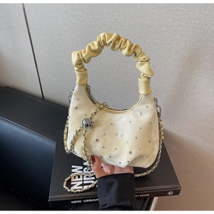 Detail of a beige ruched handbag with sparkling rhinestones and silver chain strap