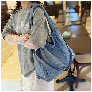 Detail of blue checkered canvas tote bag with wide strap and side pocket design