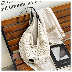 Detail of hand-woven crochet hobo bag with beige openwork pattern and black leather strap