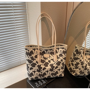 Detail of printed canvas tote bag with cow pattern and minimalist logo on premium beige background