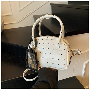 Close-up of white heart-patterned bowling bag with leather handles and card charm