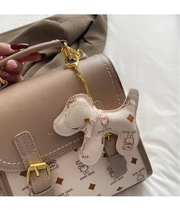 Close-up of beige tote bag with cute dog pendant and golden chain detail for women