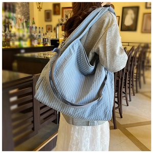 Detail of light blue quilted tote bag with wide shoulder strap worn by a model