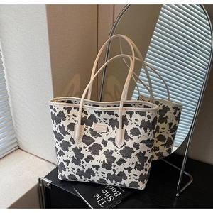 Detail of cow print tote bag with brand logo patch and mirror reflection