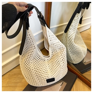 Detailed close-up of hollow crochet texture and black leather strap on a cream hobo bag