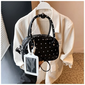 Close-up of black patent leather bowling bag with white heart pattern and luggage tag