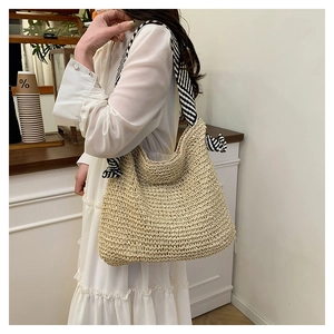 Borsa tote in paglia con manico a nastro a righe bianche e nere su abito bianco