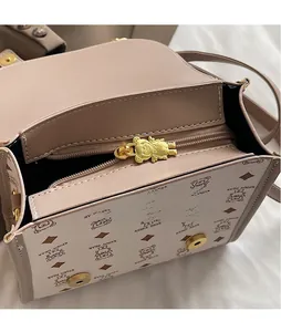 Close-up of golden bear zipper puller and Teddy Bear pattern on the beige handbag