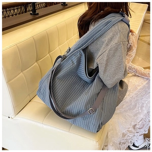 Detail of adjustable strap and blue checkered fabric texture on a large canvas tote bag