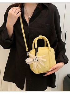 Chic yellow lychee leather Boston bag with floral charm shown as a crossbody