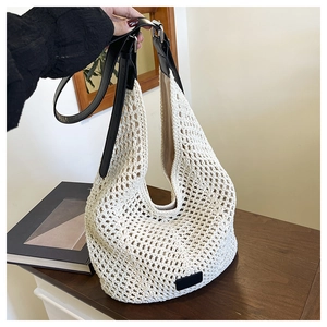 Detail of bohemian crochet tote bag featuring white woven texture and black leather strap