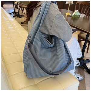 Detailed close-up of blue checkered canvas tote bag with adjustable shoulder straps