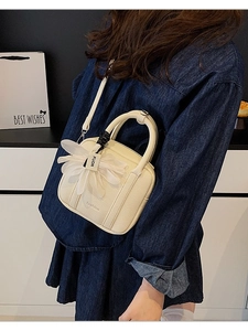 White pebbled leather Boston bag with gauze flower charm worn by a model in denim
