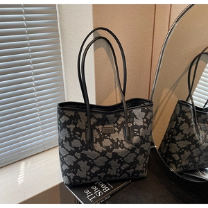 Detail of a large canvas tote bag featuring grey abstract camouflage pattern and shoulder straps