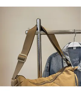 Detail of a brown dumpling bag showing its adjustable wide shoulder strap and sleek buckle