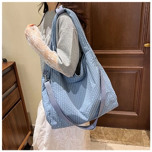 Detail showing the blue quilted texture canvas tote bag with adjustable shoulder strap