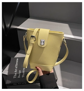 Detail of yellow leather bucket bag with silver buckle and lychee texture finish