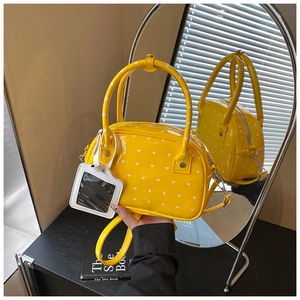 Detail of yellow patent leather bowling bag with white heart prints and card holder tag