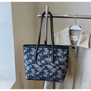 Detail of a large jacquard tote bag with leather straps on a hanger with beige trench coat