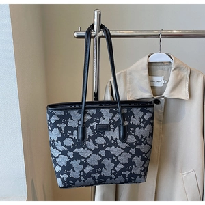 Detail of grey textured fabric tote bag with black leather handles hanging on a rack