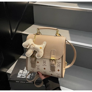 Detail of beige college-style backpack with cartoon bear print and dog-shaped charm
