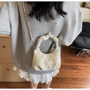 Detail of cream cloud bag featuring silver rhinestone studs and metallic chain strap