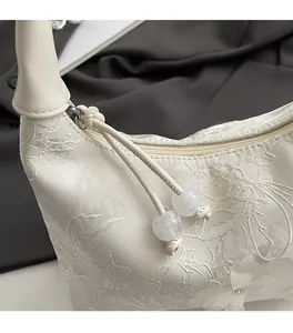 Macro shot of white satin embroidery detail with smooth metal zipper and floral decor