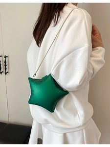 Unique star-shaped emerald green crossbody bag with gold chain strap on white outfit