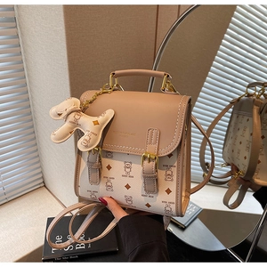 Close-up of beige crossbody bag featuring bear prints, gold hardware, and metal charm