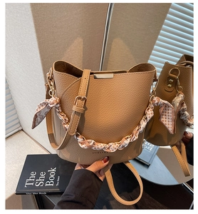 Detail of lychee textured bucket bag with silk scarf handle and golden metal buckle