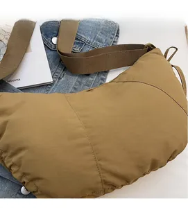 Close-up of khaki crossbody bag with wide shoulder strap on denim jacket and magazine