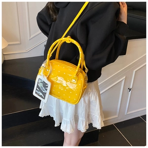 Yellow heart print crossbody bag worn with black top and white skirt in minimalist setting