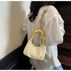 Pale yellow croissant bag with silver rhinestones and chain strap shown on a model