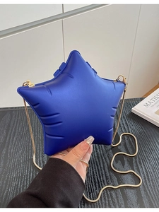 Blue star-shaped shoulder bag with gold snake chain strap on artistic background