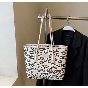 Detail of leopard print tote bag featuring a smooth PU leather finish and embossed logo tag