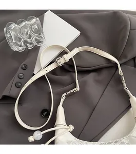 Detail of adjustable strap with silver buckle and floral lace texture on white bag