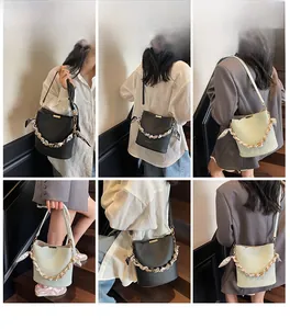 Detail shots of trendy bucket bag with metal chain and silk scarf on models