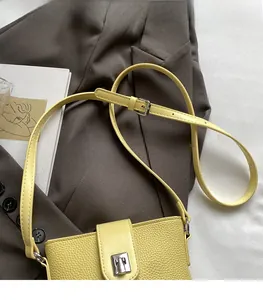Detail of light yellow lychee pattern leather crossbody bag with silver buckle